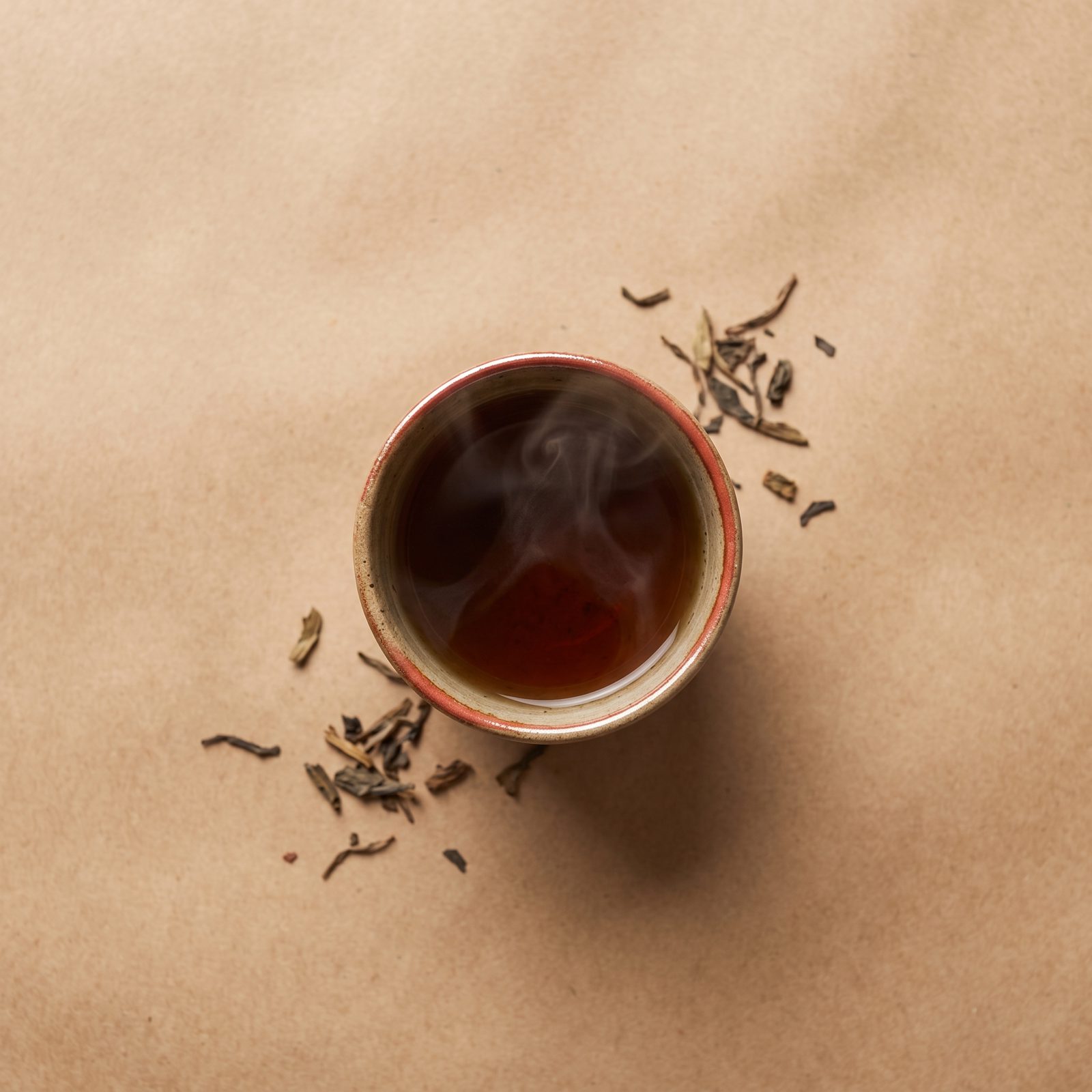 A small ceramic cup of hojicha, steam curling upward