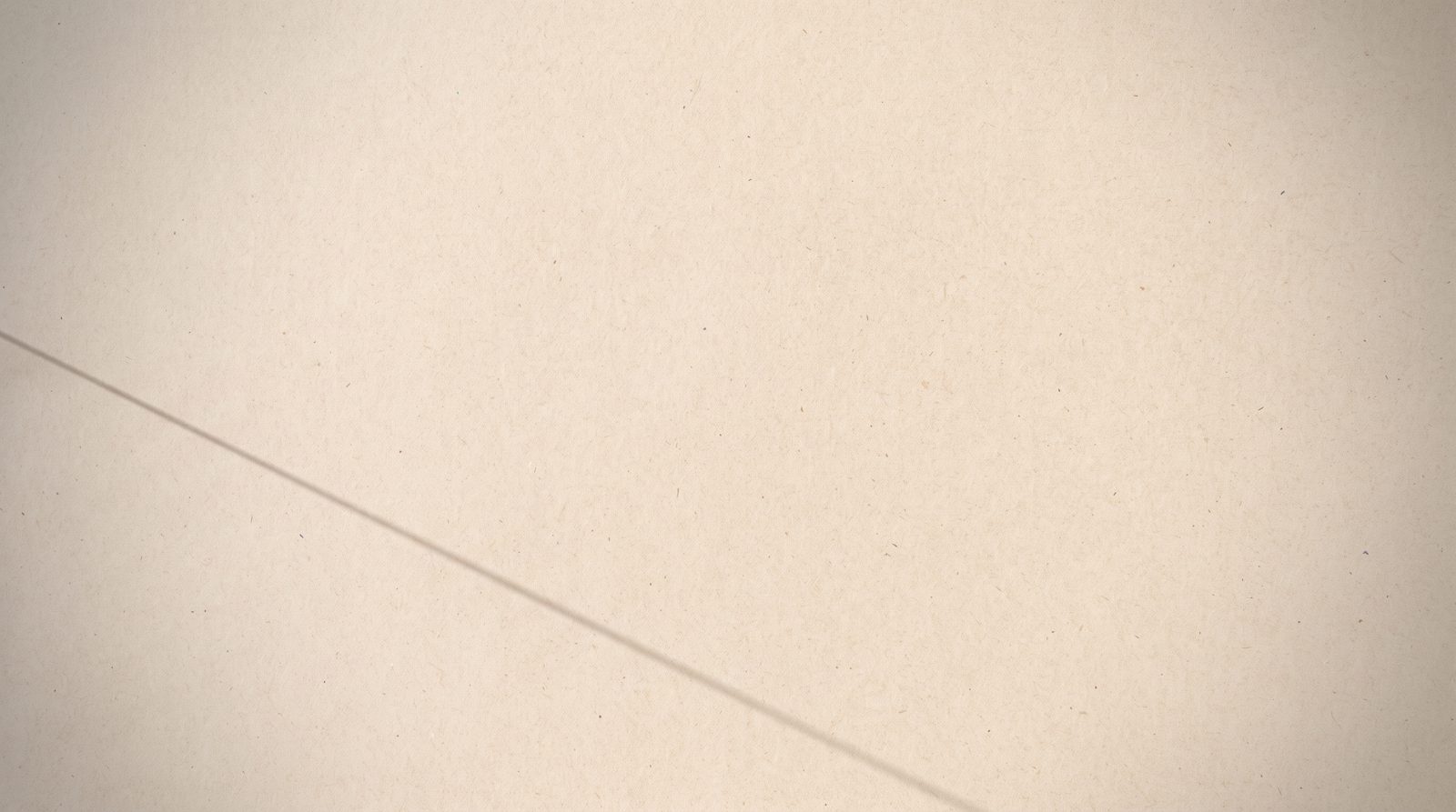 Warm kraft paper crossed by a single hairline diagonal shadow